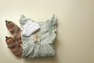 Photo of Stylish child clothes, shoes and pacifier on beige background, flat lay. Space for text