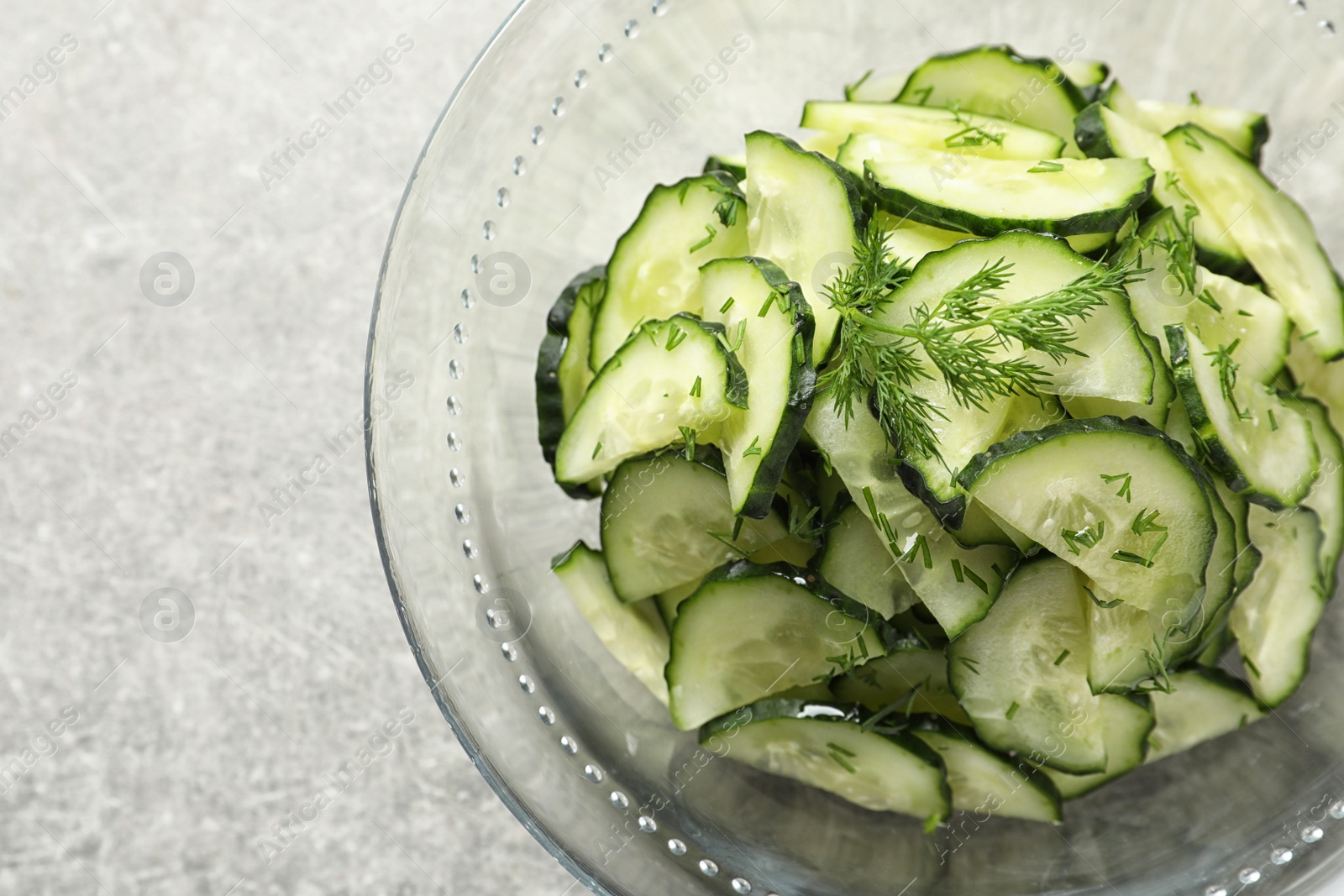 Photo of Delicious cucumber salad with dill in bowl on grey background, top view