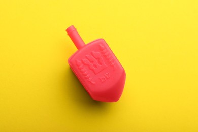 Photo of Red dreidel on yellow background, top view. Traditional Hanukkah game