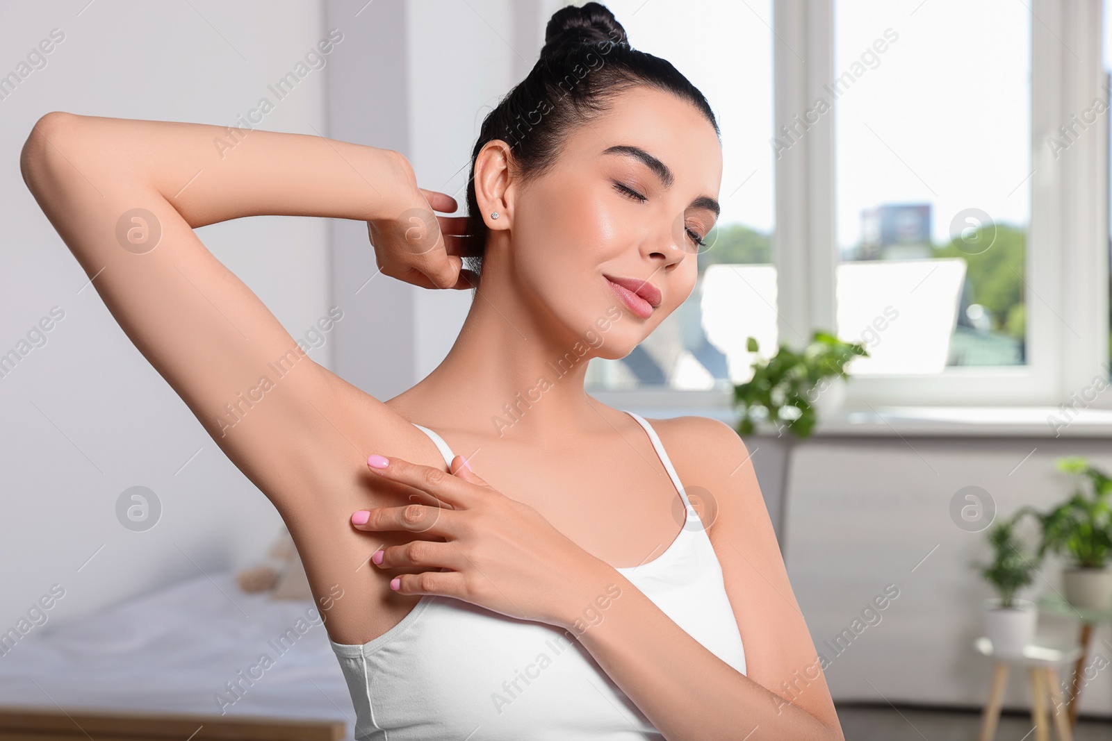 Photo of Young woman showing smooth skin after epilation in room