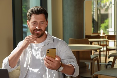 Photo of Handsome man using his smartphone in cafe