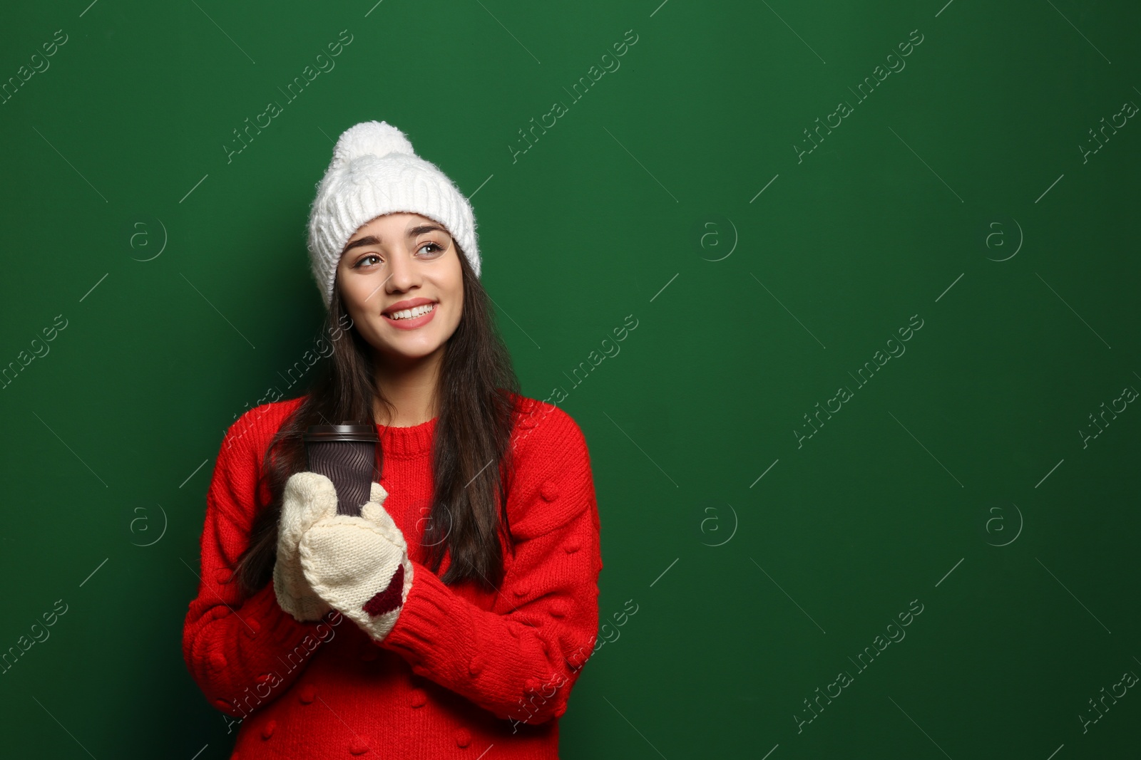 Photo of Young woman in sweater with cup of hot coffee on color background, space for text. Winter season