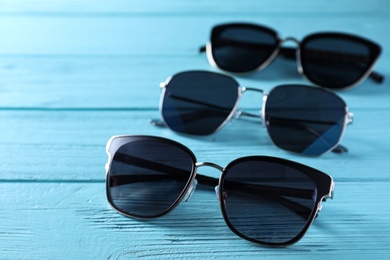Photo of Many stylish sunglasses on light blue wooden background