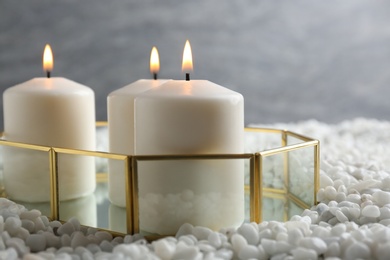 Tray with three white burning candles on rocks