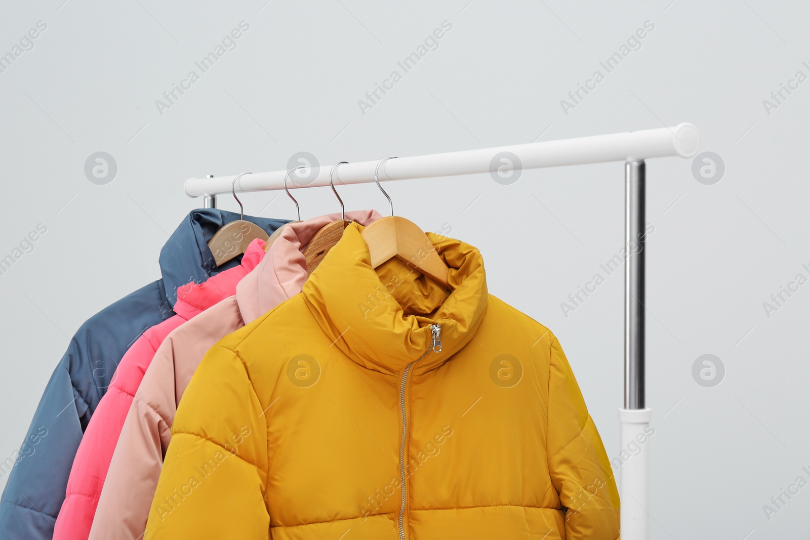 Photo of Rack with warm jackets on light background