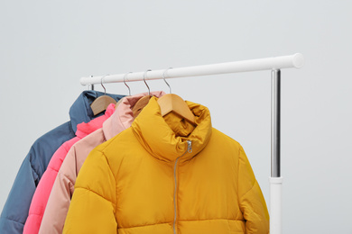 Photo of Rack with warm jackets on light background