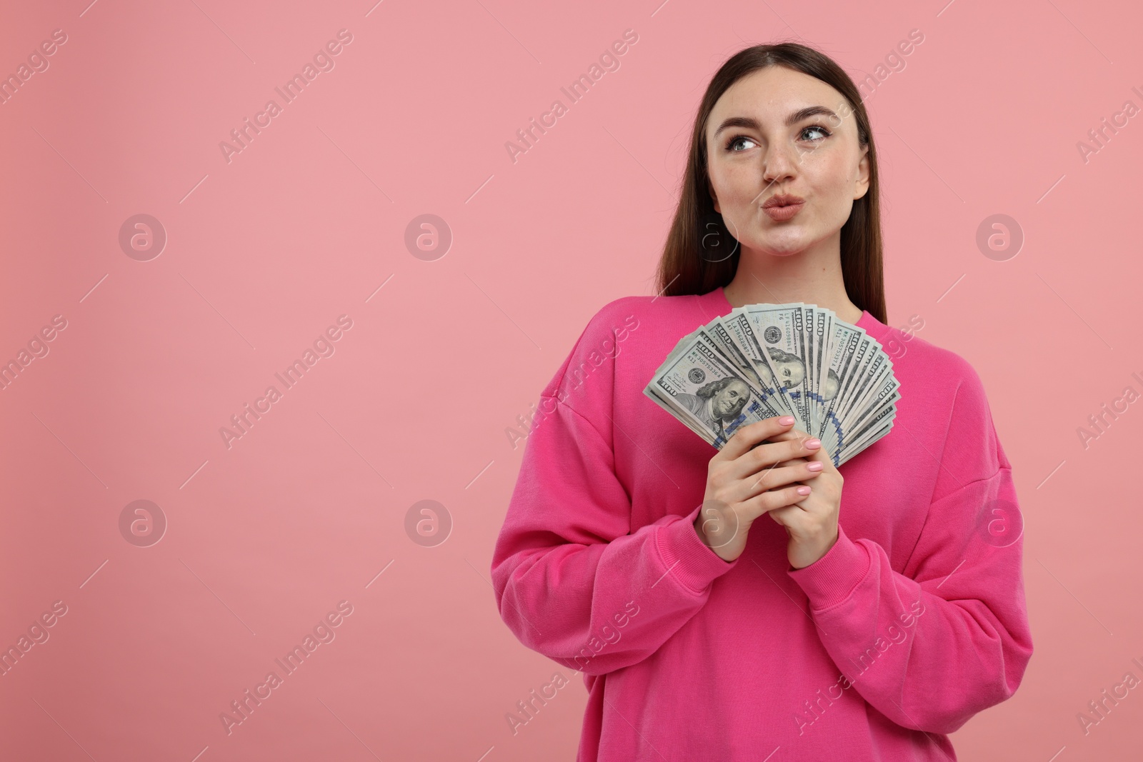 Photo of Woman with dollar banknotes on pink background, space for text