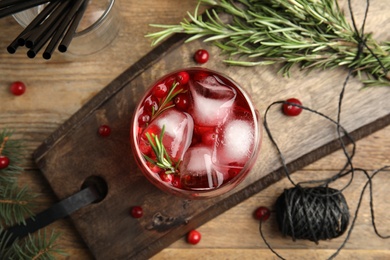 Photo of Tasty refreshing cranberry cocktail with rosemary on wooden table, flat lay