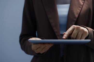 Closeup view of woman using modern tablet on grey background