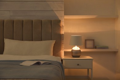 Photo of Stylish night lamp on bedside table in bedroom