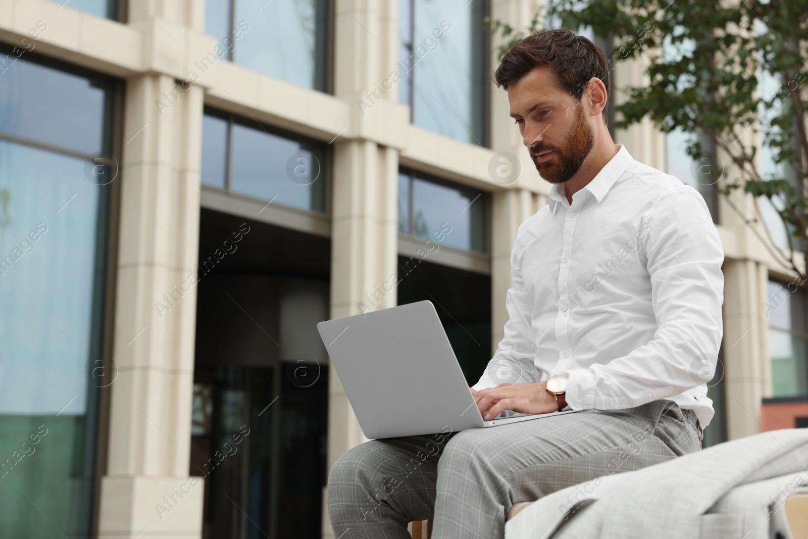 Photo of Handsome businessman with laptop on city street