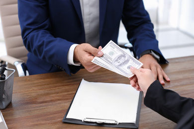 Photo of Woman giving bribe money to man at table, closeup