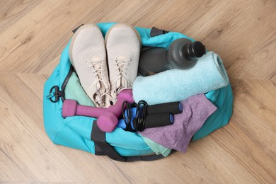 Photo of Blue gym bag with sports accessories on wooden floor, top view