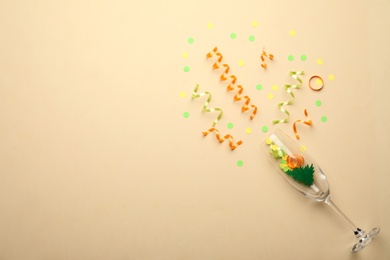 Photo of Glass and shiny confetti on beige background, flat lay. Space for text