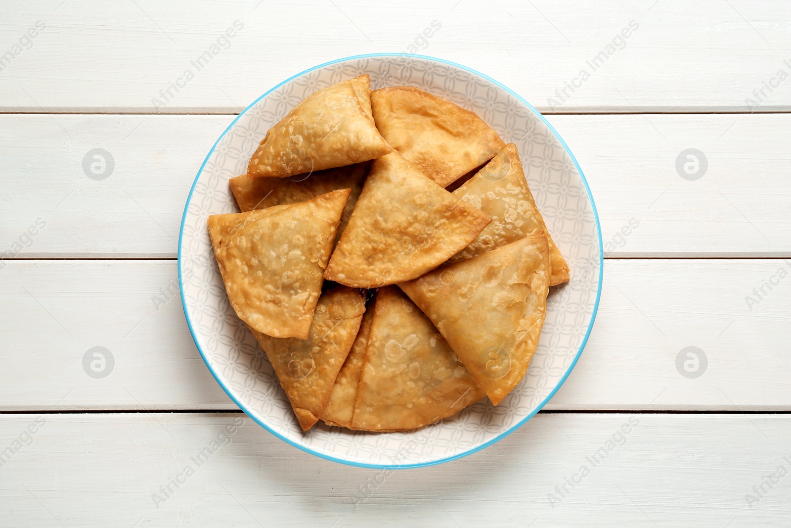 Photo of Fresh delicious crispy samosas on white wooden table, top view