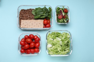 Glass containers with different fresh products on light blue background, flat lay