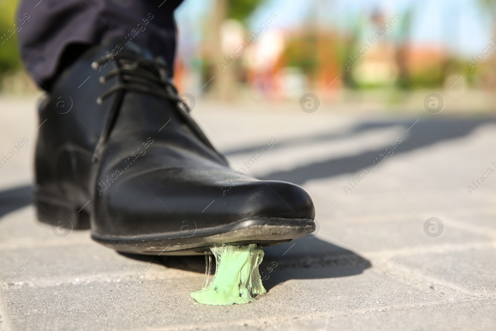 Photo of Man stepping in chewing gum on sidewalk. Concept of stickiness