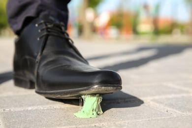 Man stepping in chewing gum on sidewalk. Concept of stickiness