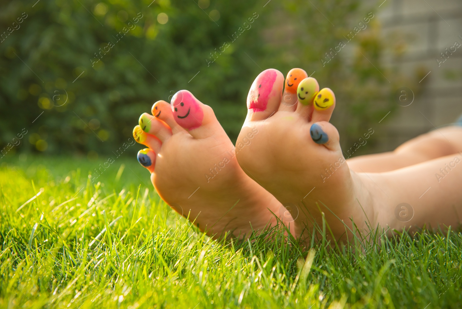 Photo of Teenage girl with smiling faces drawn on toes outdoors, closeup