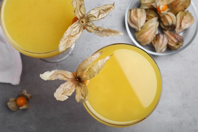 Photo of Tasty cocktail decorated with physalis fruits on grey table, flat lay