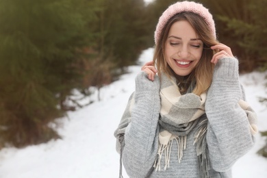 Young woman in snowy conifer forest, space for text. Winter vacation