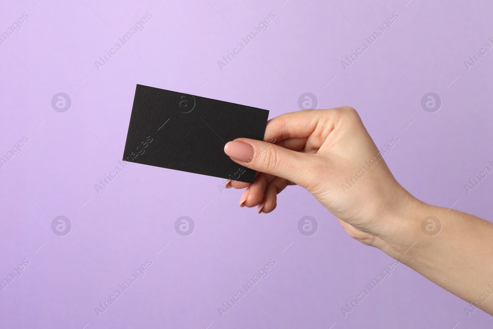 Photo of Woman with blank black business card on violet background, closeup. Mockup for design