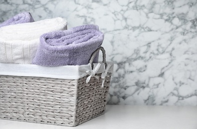 Photo of Basket with soft bath towels on table. Space for text