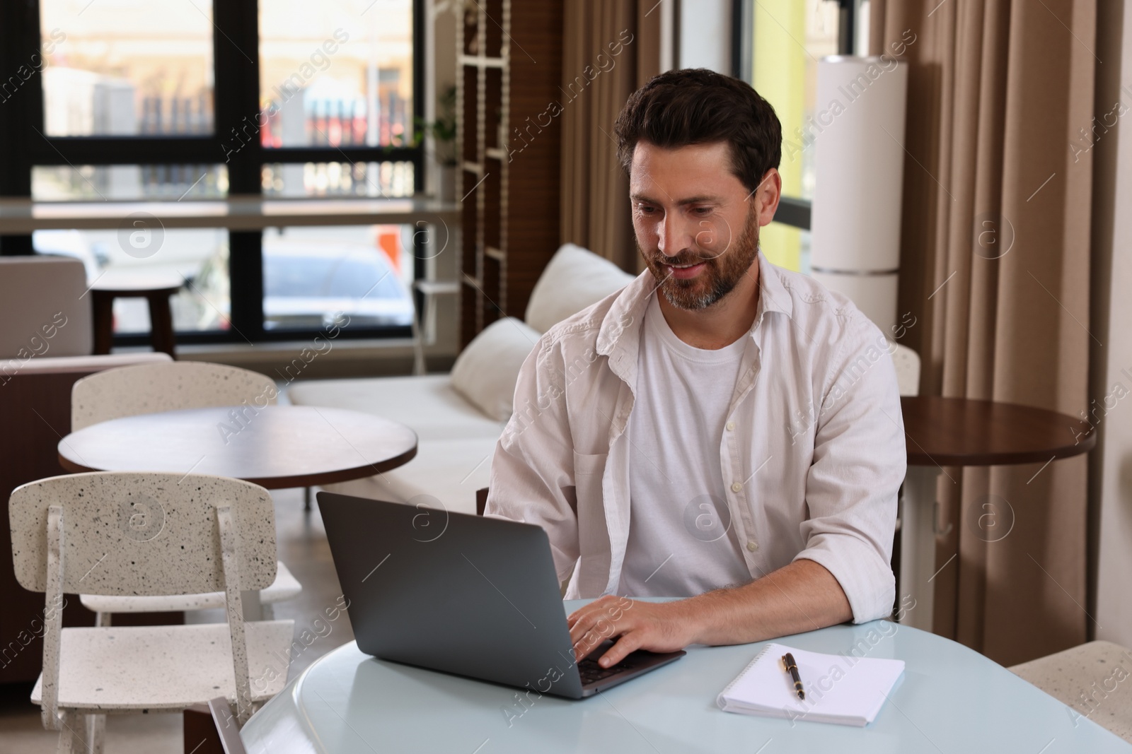 Photo of Man working on laptop at table in cafe