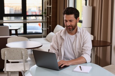 Man working on laptop at table in cafe