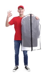 Dry-cleaning delivery. Happy courier holding garment cover with clothes and showing OK gesture on white background