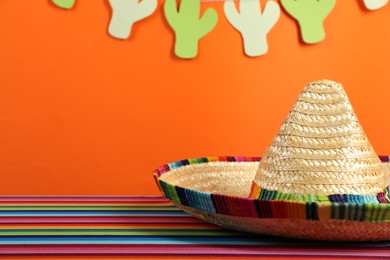 Photo of Mexican sombrero hat on color table, closeup. Space for text