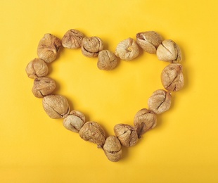 Heart shaped frame made of dried figs on color background, top view with space for text. Healthy fruit