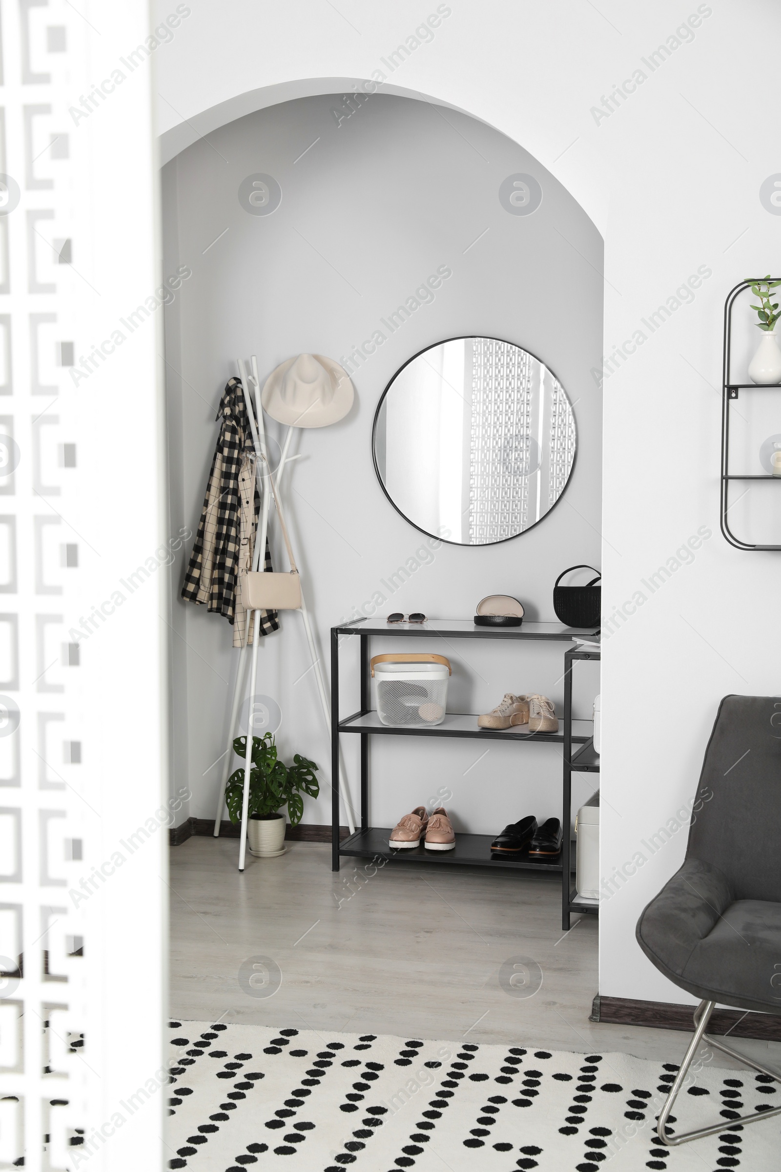 Photo of Hallway interior with stylish furniture and round mirror on light wall