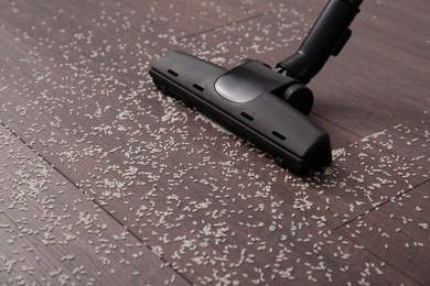 Photo of Vacuuming scattered rice from wooden floor in room