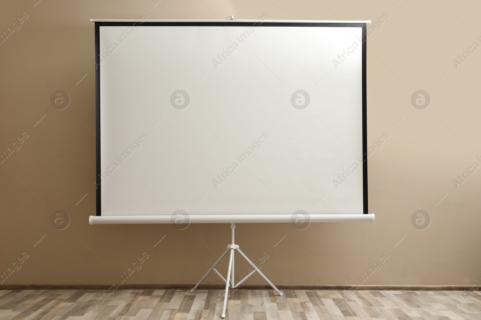 Photo of Blank projection screen near beige wall indoors. Space for design