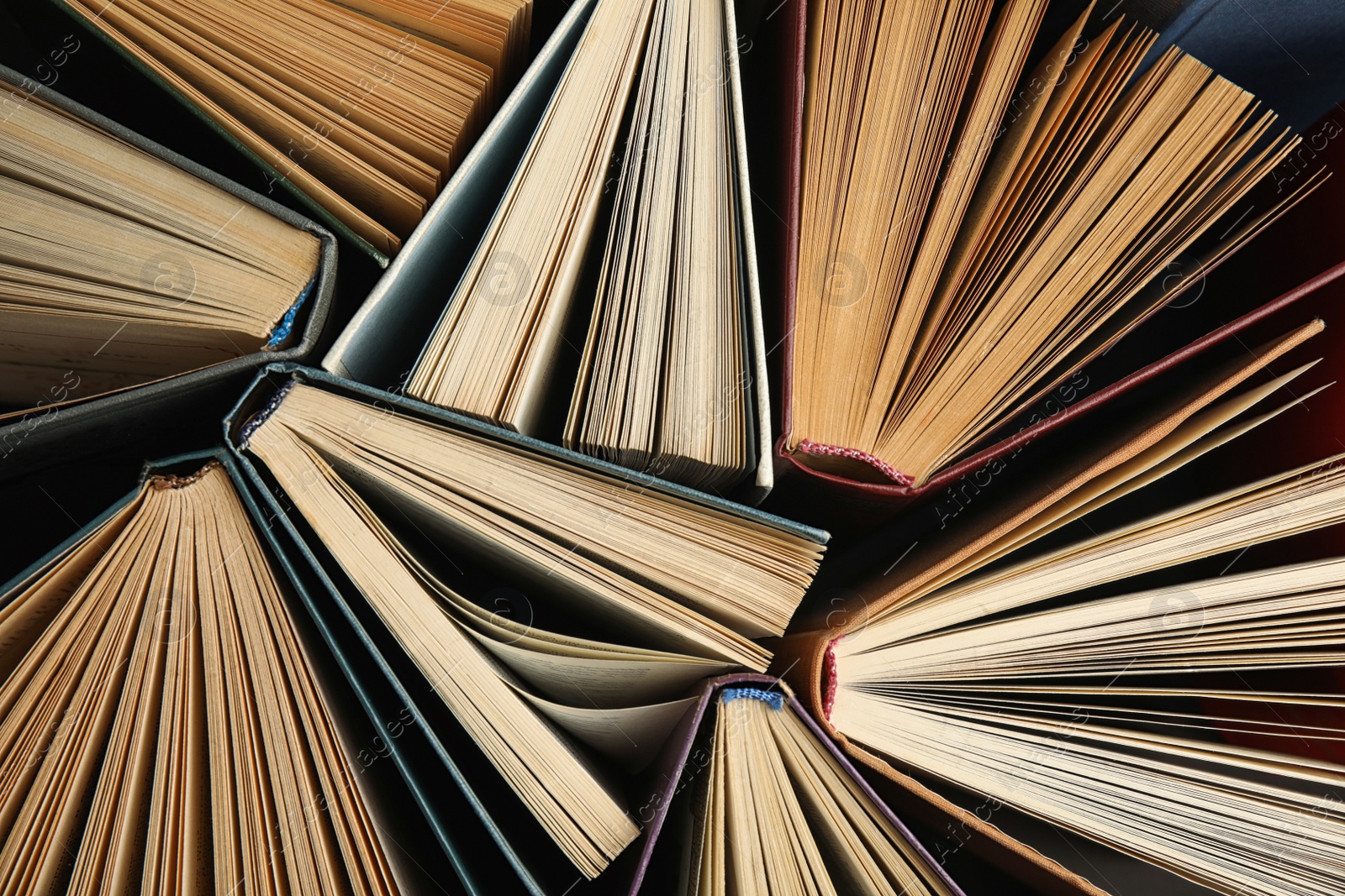 Photo of Many different hardcover books on dark background, top view