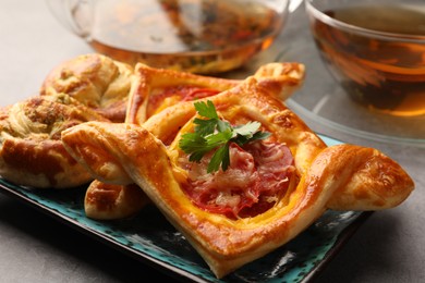 Different delicious puff pastry with tasty filling on grey table, closeup