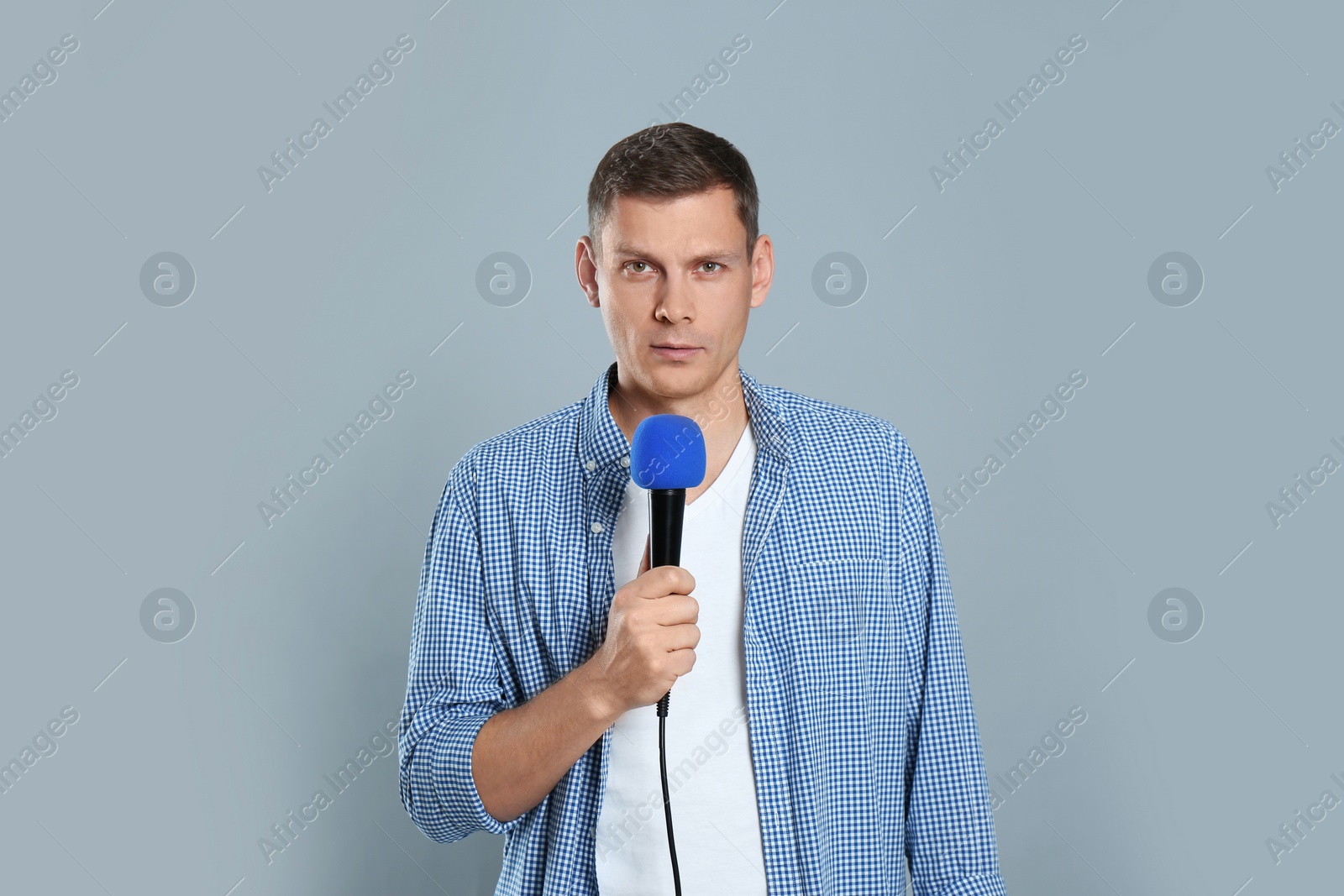 Photo of Male journalist with microphone on grey background