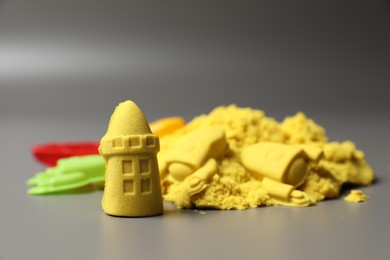 Photo of Castle figures made of yellow kinetic sand on grey background, closeup. Space for text