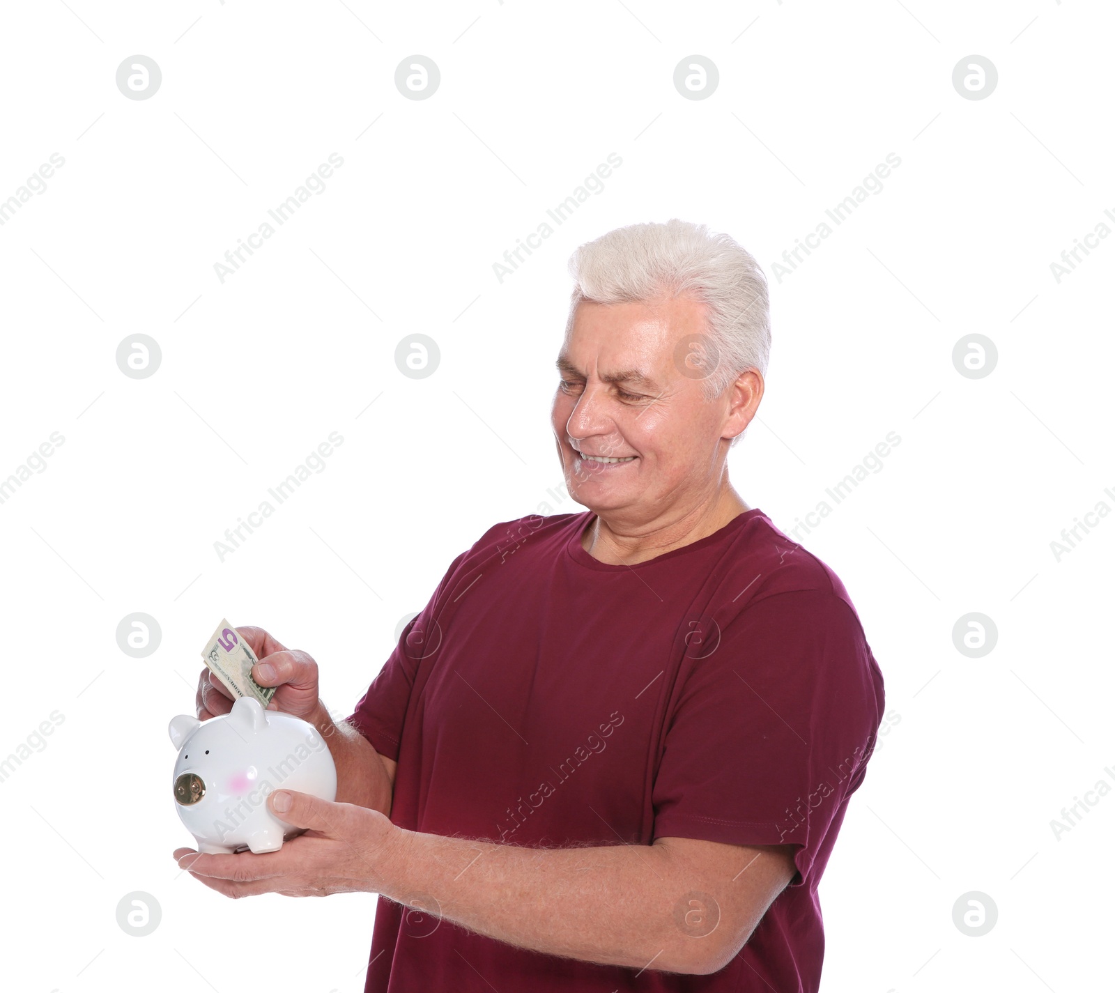 Photo of Mature man putting money into piggy bank on white background