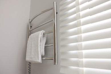 Heated rail with towel on white wall in bathroom, space for text