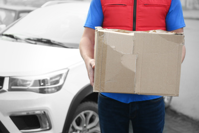 Photo of Courier with damaged cardboard box outdoors, closeup. Poor quality delivery service