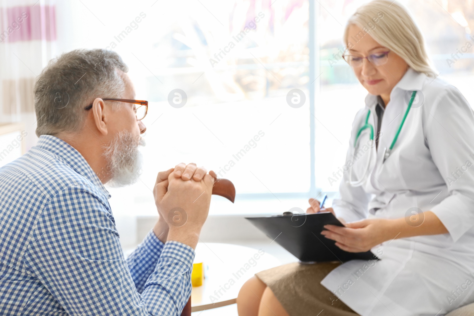 Photo of Mature doctor consulting patient at home