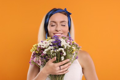 Happy hippie woman with bouquet of flowers on orange background