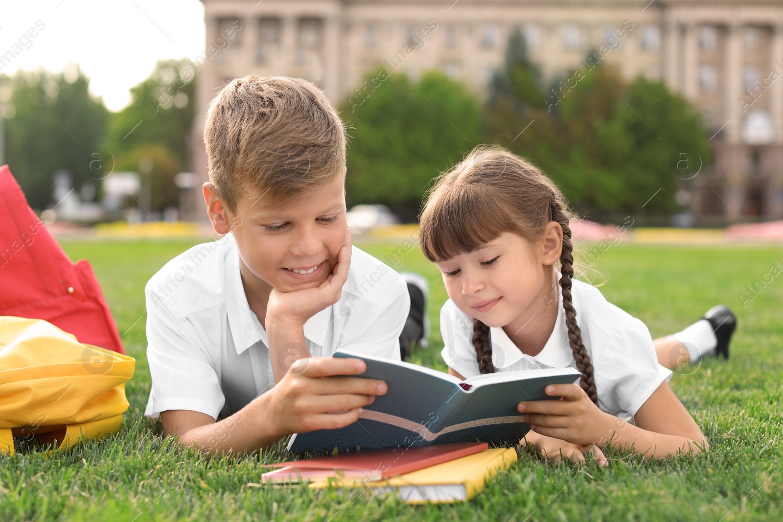 Photo of Children with stationery doing school assignment on grass outdoors