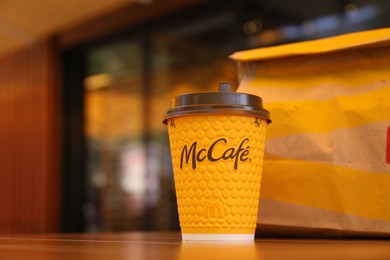 Photo of MYKOLAIV, UKRAINE - AUGUST 11, 2021: Hot McDonald's drink and packed food on table in cafe. Space for text