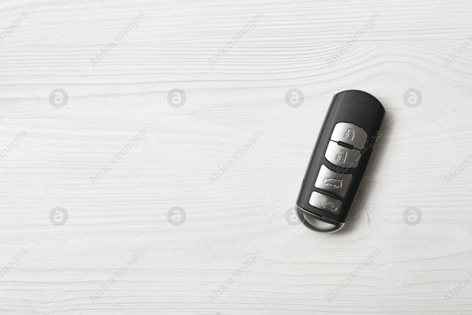 Photo of Remote car key on white wooden background, top view. Space for text