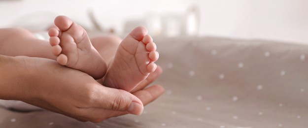 Image of Mother and her little baby on bed, closeup view with space for text. Banner design