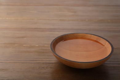 Photo of Bowl with clear water on wooden table. Space for text