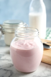 Glass jar of fresh yogurt on table